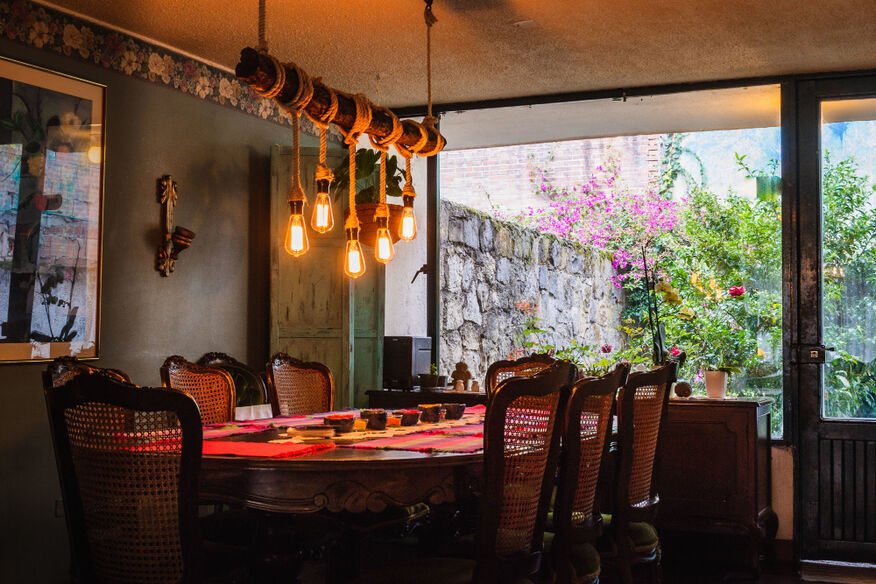 The cozy and inviting interior dining room of Curry Express featuring rustic wooden tables, vintage chairs, and warm pendant lighting.